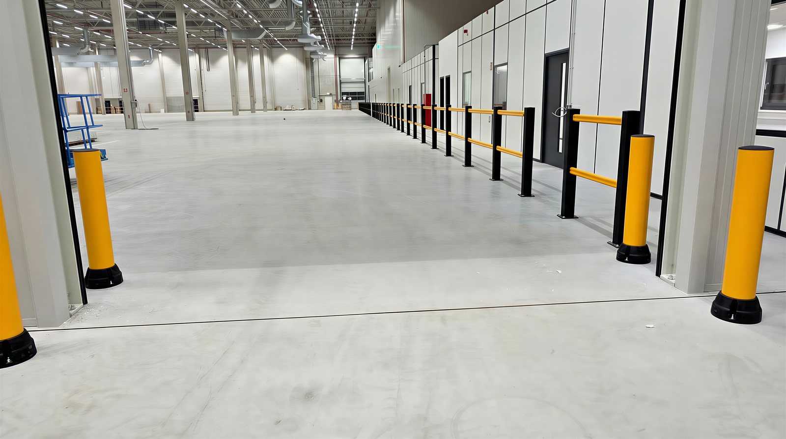 Schwarzes Schutzgeländer mit gelben Planken in einer Industriehalle
